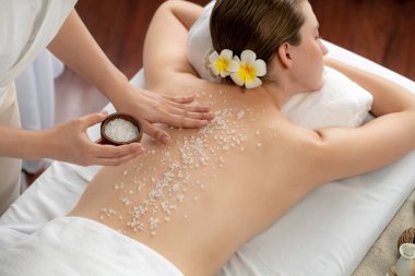 Lüks spa salonlarında sıcak mum ışığında cilt bakımı yaptıran kadın müşteri. Sağlık Spa vücut fırçasında tuz temizleme güzellik tedavisi. Sessiz.