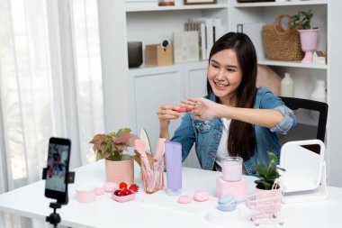 Genç, güzel Asyalı kozmetik makyaj ruju matte pastel rengini modern odadaki sosyal medyada kol testi tanıtımında en çok satanlar listesinde gösteriyor. Taktik.