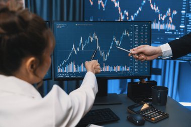 PC ekranlarında dinamik borsa istatistiklerini tartışan iş ortaklarının kağıt üzerinde not alması, para birimi grafiğindeki yüksek ya da düşük nokta ile gece neon çağındaki modern ofis karşılaştırıldığında. İnfobahn.