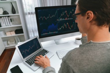 Bilgisayar ve dizüstü bilgisayarı kullanarak, çalışma masasındaki dinamik artırılmış borsa grafiğinin en yüksek kar değerini araştıran bir tüccar, modern ofisteki ekrandaki döviz kuru değerini analiz ediyor. Bireysel.