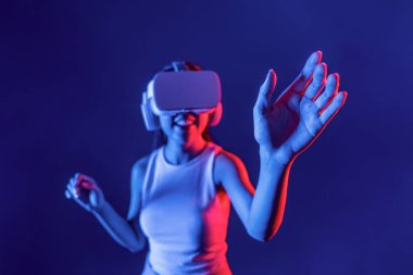 Siberpunk neon ışığı altında duran zeki kadın metaevrene bağlı VR kulaklık takıyor, gelecekçi siber uzay topluluğu teknolojisi. Zarif bir kadın, elde üretilen sanal objeye dokunur. Halüsinasyon.