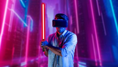Lazer kılıcı tutan ve VR gözlük takan oyuncu. Beyaz adam, neon şatonun etrafında dikilirken görsel gerçeklik kulaklığı kullanıyor. Yenilik teknolojisi. Sapma.