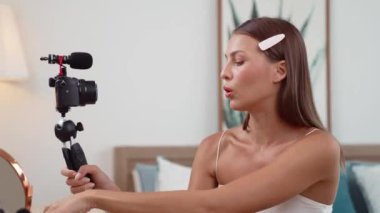 Sosyal medya için güzellik ve kozmetik video içeriği hazırlayan genç bir kadın. Güzellik blogcusu kameraya gülümserken seyircilere ve takipçilere güzellik bakımını gösteriyor. Düzenle