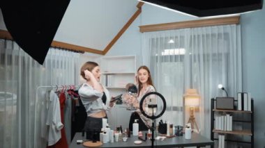 Etkilenen iki ortak canlı yayında video görüntülerini çekiyor makyaj malzemesi prim sosyal medya veya blog. Kozmetik stüdyosu ışıklandırmalı mutlu genç kız çevrimiçi pazarlama oturumu yayını için..