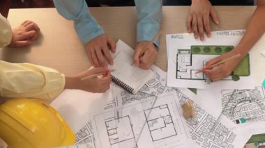 Mimari belge, ölçüm aracı ve ahşap blokların modern ofiste etrafa saçıldığı bir masa üzerinde yapı inşaatı ile ilgili mimar ve güvenlik mühendisi tartışması. Tanımlama.