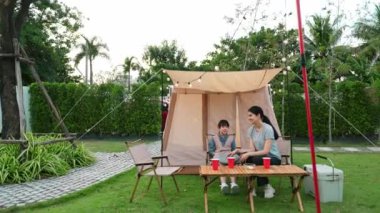 Aile hep birlikte bahçedeki kampta oturup yemek yiyor. Ebeveynler, genç nesil arasında iletişim kurmak ve zaman geçirmek için açık hava kamp faaliyetlerini kullanıyorlar. Uyumsuzluk.