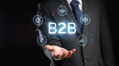 İş adamı B2B peyzajında geziniyor, iş ile iş arasındaki bağlantıları geliştirmek için teknolojiyi kullanıyor. B2B etkileşimlerini yeniden şekillendiren, iş-iş stratejilerinde yeniliği teşvik eden keşifler