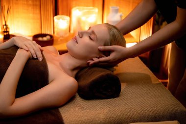 Beyaz kadın stres önleyici kafa masajı yapmaktan ve lüks otel veya otelde sıcak mum ışığında yüz güzelliği eğlencesi yapmaktan zevk alıyor. Sessiz.