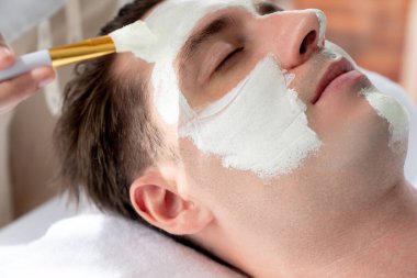 Kaplıca salonunun sakin atmosferi, insan müşterisi modern gün ışığında lüks yüz kremi masajıyla kendini yenileme zevkine kapılıyor. Yüz bakımı ve güzellik konsepti. Sessiz.