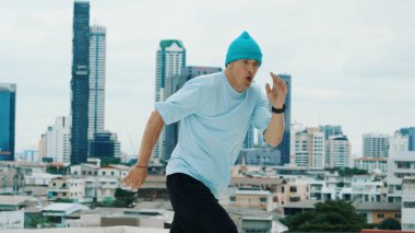 Beyaz dansçı çocuk şehir veya şehirle çatıda sokak dansı yapıyor. Genç adamın sokak dansı yaparken dondurucu poz vermesi. Break dans. Açık hava sporu 2024. Hiphop.