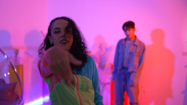 Çekici mutlu dansçı kameraya bakarken zeki kadın neon ışıkla kafiyeli hareket ediyor. Profesyonel İspanyol şarkıcı çeşitli arkadaşlarıyla renkli kıyafetler giyerken break dans yapıyor. Mutluluk.