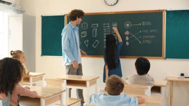 Genç Asyalı kız sınıfta dururken tahtada matematik formülü yazıyor. Çekici ilköğretim öğrencisi matematik dersinde çalışırken ya da soru cevap verirken. Eğitim konsepti. Pedagoji.