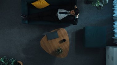 Stresi azaltmak için kanepede yatarken dizüstü bilgisayarda çalışan iş adamlarının yukarıdan görünüşü. Stresli, akıllı işçi koltukta uyurken iş planı ya da pazarlama stratejisi düşünüyor. Müdürlük.