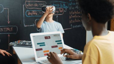 Kafkasyalı kız tahtada mühendislik kodlarıyla otururken Afrikalı erkek programlama sistemi. Liseli kız STEM teknolojisinde VR ya da kulaklık takıyor. Öğretim.