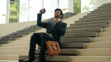 Başarılı bir iş adamı merdivenlerde otururken başarılı bir projeyi kutluyor. Akıllı proje yöneticisi yeni bir iş buluyor, terfi alıyor, telefonla arkadaşlarını ararken satışları arttırıyor. Sevinçli..