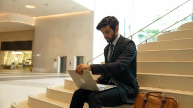 Merdivenlerde dizüstü bilgisayar kullanarak çalışan ya da plan yapan yetenekli bir yatırımcı. Modern bir otelde dizüstü bilgisayar kullanarak veri analizi yapan takım elbiseli profesyonel bir iş adamı. Sevinçli..