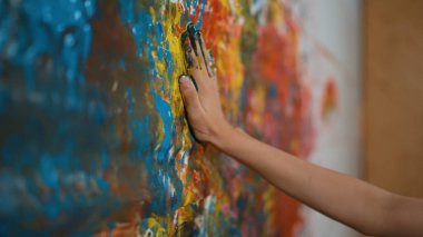 Renkli duvara yerleştirilmiş liseli kız elinin yan görüntüsü ve elini çek. Resim dersinde odanın kapatılması ya acı verici ya da el iziyle süslenmişti. Yaratıcı aktivite konsepti. Öğretim.