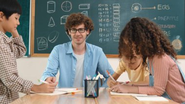 Zeki öğretmen, çeşitli çocuklar sınıf çalışması yapmak için birlikte çalışırken farklı çocukların zihin haritası çizdiği fikri açıklıyor. Çekici eğitmen öğretmek ve çalışmak hakkında konuşmak. Pedagoji.