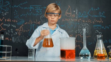 Akıllı çocuk, laboratuvar şişelerinde karışık kimyasal sıvıları dikkatlice inceler. Beyaz çocuk kimya dersi ya da BTMM fen dersinde bir deney yapmaya odaklan. Etkinlik.