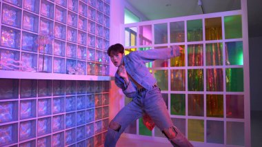 Gece kulübünde kameraya bakarken güneş gözlüklü Asyalı dansçı serbest dans ediyor. Mutlu sokak dansçısı dans ediyor ve renkli parlak neon ışığı ya da yol gösteren ışıkla ayak seslerini gösteriyor. Mutluluk.