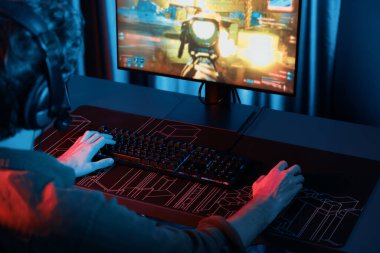 Genç oyun flamasının sunucu kanalı, bilgisayar ekranında çoklu oyuncuyla savaş oyunu oynayan, dijital neon odasında mikrofonlu kulaklık takan bilgisayar. Toplayıcı.