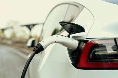 Kapalı EV şarj kolu fişe takıldı veya elektrikli arabaya bağlandı, EV araba aküsünü temiz çevre için sıfır CO2 emisyonu ile alternatif ve sürdürülebilir enerjiyle şarj etti. Kalıcı