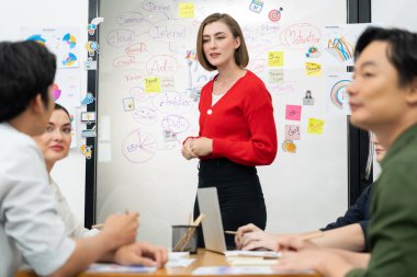 Profesyonel çekici kadın lider, modern iş toplantı odasında beyin fırtınası zihin haritalama istatistikleri ve renkli yapışkan notlar kullanarak yaratıcı pazarlama planını sunuyor. Tertemiz..