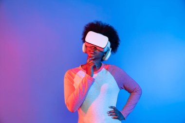 Profil, VR gözlük takan genç ve güzel Afrikalıların mavi ve pembe neon ışıklı arkaplanda izole olduğunu düşünüyor. Teknoloji ve dijital yenilik 3 boyutlu hologram gramında. Entrika.
