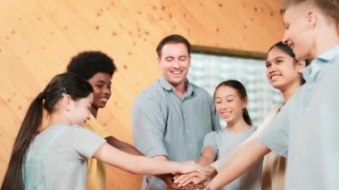 Kafkas öğretmeni ve mutlu çeşitli çocuklar ayakta dururken başarılı projeyi kutlamak için el ele tutuşuyorlar. Aşkı, şirketi, takım çalışmasını, birlikteliği ve birliği temsil et. Öğretim