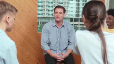 Öğrencilerle grup terapisinde konuşurken zihinsel sorunları çözmek için yetenekli beyaz bir öğretmen konuşuyor ya da fikir paylaşıyor. Çocuklara tavsiye veren ya da psikoterapiye katılan bir eğitmen. Öğretim