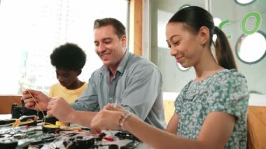 Yetenekli öğretmen Afrikalı çocuğa elektrikli aletleri açıklarken liseli kız model tamir ediyor. Çok kültürlü bir öğrenci robot araba yapımı ve elektronik aletleri öğreniyor. Öğretim