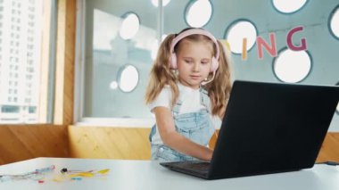 Kafkasyalı kız kulaklık takıyor ve mekanik okurken dizüstü bilgisayara bakıyor. Bilgisayarla çalışan yetenekli bir öğrenci masadaki elektrikli aletleri araştırıyor ve öğreniyor. Akıllı sınıf. Etkinlik.