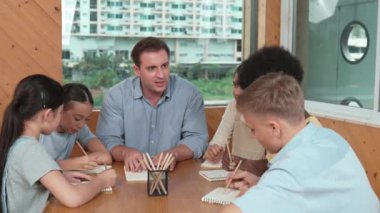 Çok kültürlü çocuklar resim çizerken ya da masa başında kalemle kağıt üzerinde not alırken zeki öğretmen konuşuyor ve işi anlatıyor. Otururken çeşitli öğrenci çizimleri ya da paylaşım fikirleriniz kutlu olsun. Öğretim