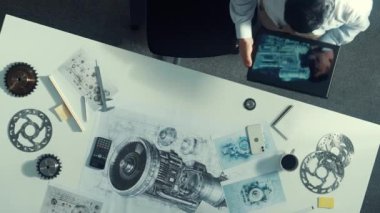 Motoru öğrenirken makinistlerin tablet tutuş tabletinin yukarıdan aşağıya görüntüsü. Masada yürürken tablete bakan ve türbin motorunu kontrol eden yetenekli proje yöneticisinin havadan görünüşü. Hizalama.