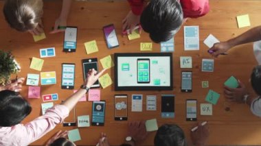 Ux ui tasarımını renkli yapışkan nota üzerine yazmak için birlikte çalışan geliştirici ekibinin üst görüşü. Tablet 'te kablo prototipi inceleyen ve yazılım tasarlayan bir grup programcı. Cemaat.