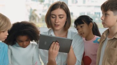 Bir grup öğrenciye çevrimiçi ders verirken elinde tablet tutan akıllı öğretmen. Yetenekli eğitmen mühendislik derslerini anlatırken genç öğrenci oturuyor ve sunumu dinliyor. Etkinlik.