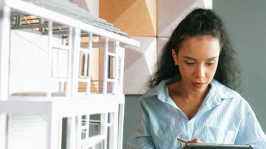 Yetenekli genç, güzel İspanyol mimar mühendis ev yapısını analiz etmek için tablet kullanmaya karar verdi. Profesyonel başarılı iş kadını ev modelini kontrol ediyor ve yatırım yapmaya karar veriyor. Yönlendirici.