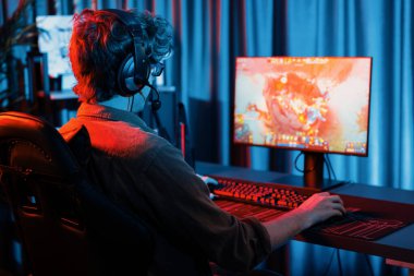 Savaş arenasında çoklu oyunlar takımıyla Moba 'da savaşan genç oyun flamasının sunucu kanalı, neon dijital ışık modern odasındaki arka görüntü ile bilgisayar monitöründe kulaklık takıyor. Toplayıcı.