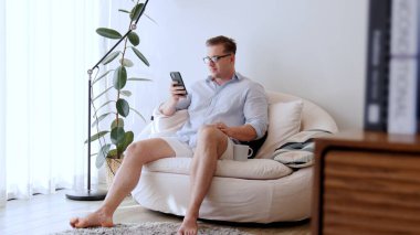 Orta yaşlı bir adam, iş için telefon arama verilerini kullanarak, çocukları iyi bir yetişkin ya da eğlence olsun diye odada kahve fincanıyla koltukta oturur. İşadamı teknolojiyi kolaylık için kullanır. Uyumsuzluk.