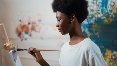 Afrikalı erkek tuvali sıcak tonda boyarken, beyaz elbiseli kız renkli duvarın arkasında havalı renkler çiziyor. Yaratıcı aktivite konsepti. Öğretim.