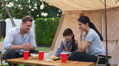 Aile hep birlikte bahçedeki kampta lezzetli atıştırmalıklarla oturuyor. Sevimli ebeveynler, genç nesil arasında iletişim kurmak ve zaman geçirmek için açık hava kamp faaliyetlerini kullanırlar. Uyumsuzluk.