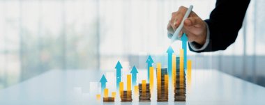 Dijital grafik göstergeli bozuk para yığını iş yatırımını ve ekonomik büyümeyi sembolize ediyor. Finansal hedefe ulaşmak ve kâr sağlamak için finansal planlama yapan bir iş adamı. Kurnaz.