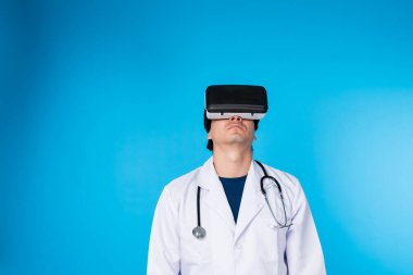 Metatik analitik tıp araştırmalarını birleştiren VR kulaklığına bakan zeki doktor mavi arka plan fütüristik teknoloji hologramı sanal gerçeklik akıllı meta dünya. Entrika.
