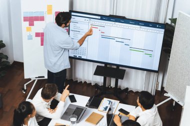 Proje yöneticisi monitörde proje yönetimi yazılım görüntülemesi, proje görevinin ilerlemesini izlemek ve toplantı masasında program planı yapmak suretiyle ekiple iletişim kurar ve işbirliği yapar. Tedbirli