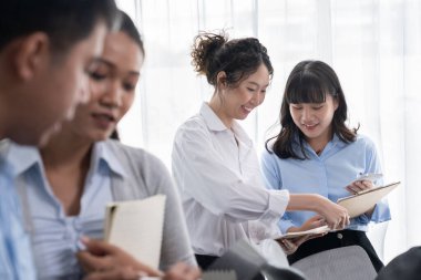 Gülümseyen Asyalı ofis çalışanı arkadaş canlısı ofis ortamında birlikte çalışıyor. İş yerinde, üretken bir ekip çalışması ve paylaşım fikri olan bir grup mutlu iş adamı. Çok titiz.