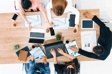 Modern ofisteki iş adamları ve iş kadınlarıyla grup toplantısındaki iş adamlarının en üst düzey görüşü, masada dizüstü bilgisayar, kahve ve belge ile. Kurumsal şirketler uds