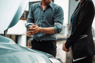 Erkek kadına araba sorununu çözmesi için yardım eder. Hasarlı parçayı tamir etmek için arabanın kaputunu açtı. uds