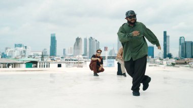 Profesyonel break dans takımı çatıda çok kültürlü arkadaşlar varken break dans alıştırması yapıyor. Genç modern dans grubu hip hop hareketi yapıyor. Tarz, moda, aksiyon. Açık hava sporu 2024 hiphop..