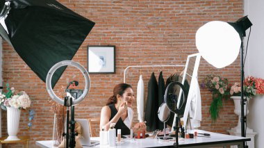 Kadın nüfuzlu kişi canlı yayın yapan video görüntülerini sosyal medya ya da blog üzerinden gözden geçiriyor. Kozmetik stüdyosu ışıklandırmalı mutlu genç kız çevrimiçi pazarlama oturumu yayını için..