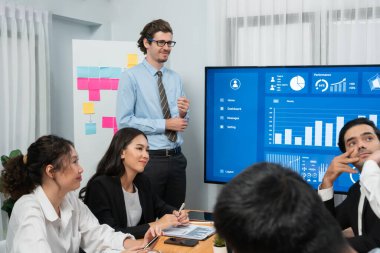 İş adamı, finansal rapor veri analizi veya pazar eğilimi gösterisiyle iş sunumunu şirketin gelecekteki yönetiminde stratejik planlama için büyük bir TV ekranında sundu. Habiliment